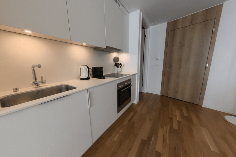 modern kitchen with white cabinets, stainless steel sink, white counter, gas stove, wooden floor