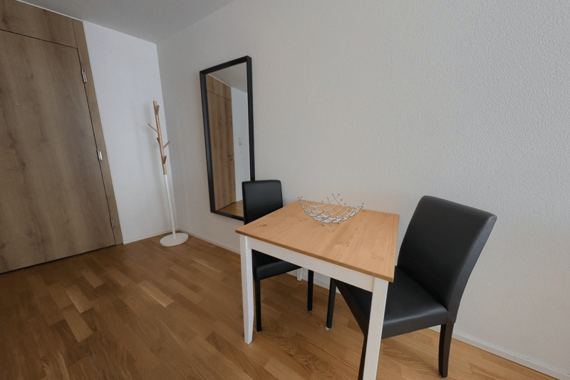 empty room with wooden floor, dining table with 2 chairs, mirror, closet, coat rack