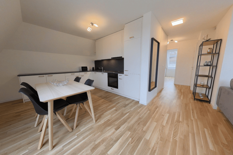 Wooden floor, white kitchen cabinets, black microwave, oven, dining table, black chairs