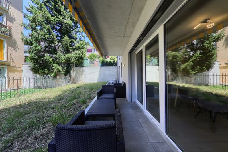 Balcony with outdoor furniture, glass doors, and a grassy area