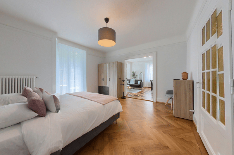 bedroom with bed, hardwood floor, closet, wardrobe, radiator, couch, table with vase