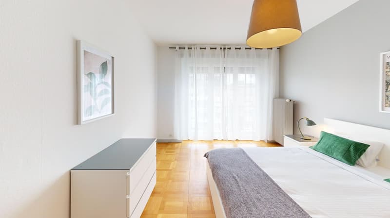 Bedroom with wooden floor, white walls, bed, nightstands, lamp, picture frame, white curtains, radiator