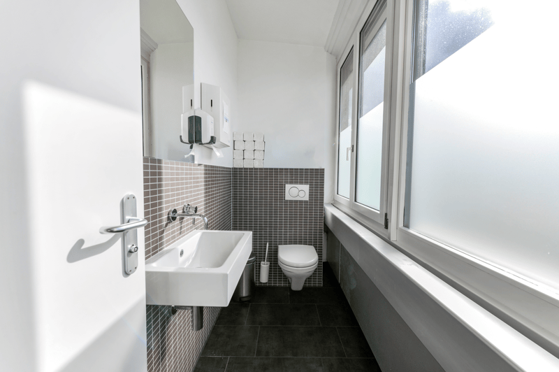 small bathroom with white sink, toilet, mirror, and window