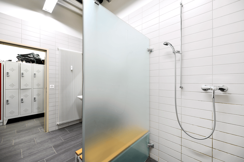 White tiles, glass shower wall, white benches, chrome faucet, white toilet