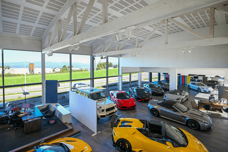 modern, large showroom, multiple cars, glass walls, wooden office tables