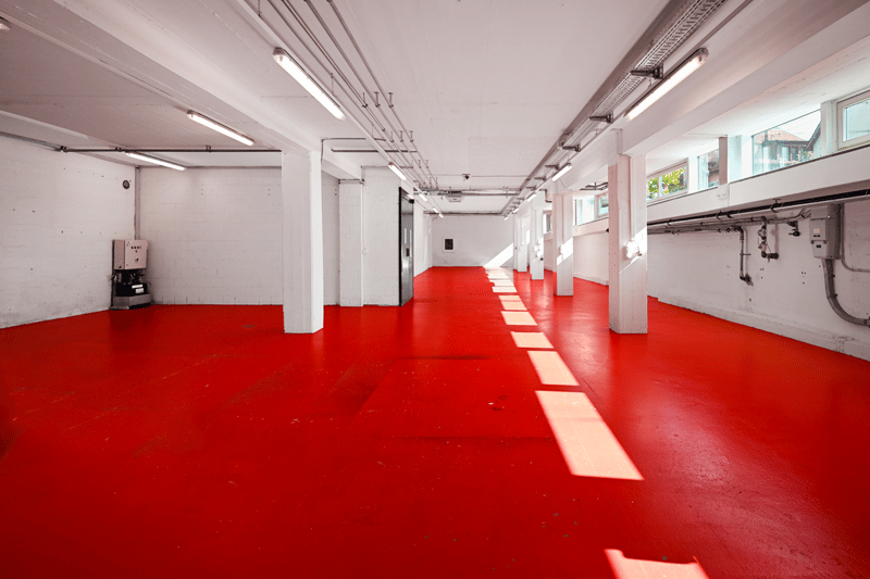 white walls, red floor, windows, central passage, pipes, columns