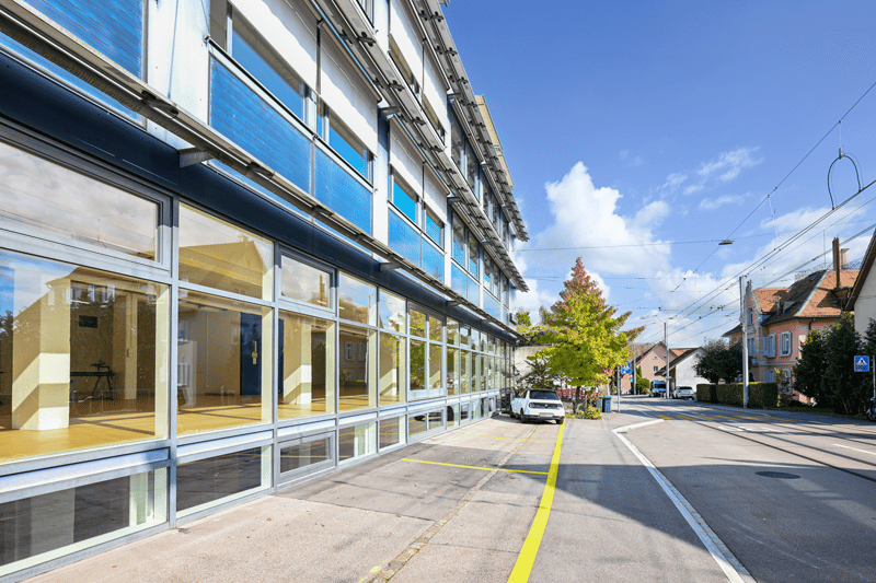 modern building with glass walls and large windows, street view, parked car
