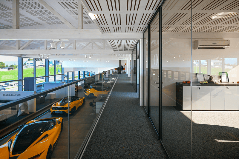 showroom with 3 sports cars on display, large windows, large central corridor, white walls and ceiling