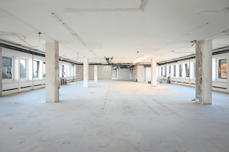 open space, several pillars, wires on ceiling, large windows