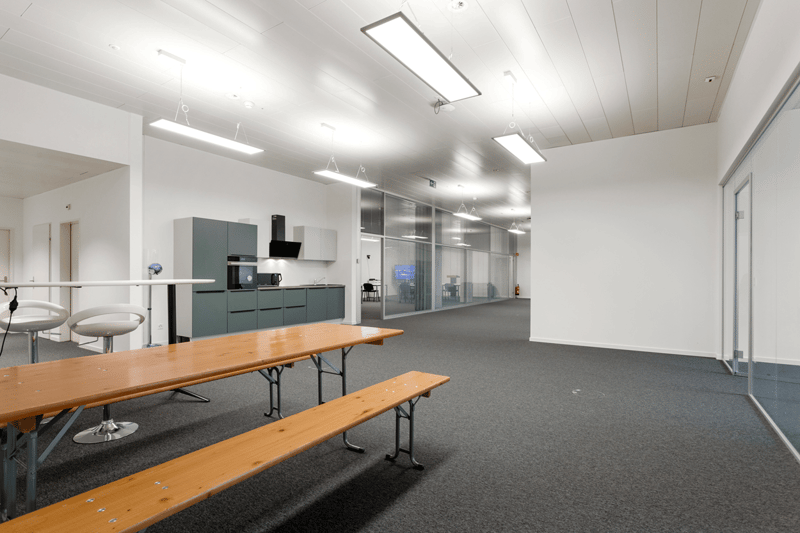 empty large room, two long benches, two bar stools, kitchen, hanging lamps