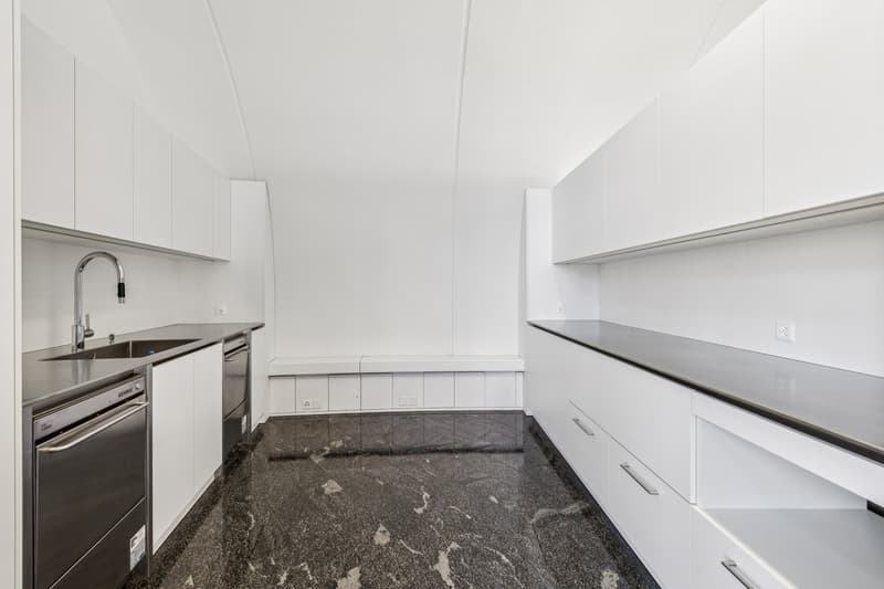 Modern kitchen with white cabinets, granite countertop, stainless steel appliances, including a dishwasher and washing machine
