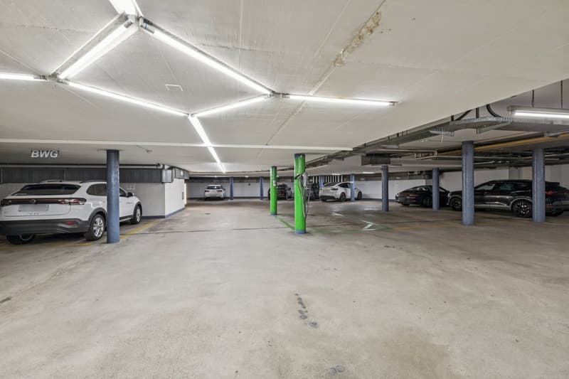 multiple parked cars, charging stations, green and yellow lines, illuminated with overhead lights