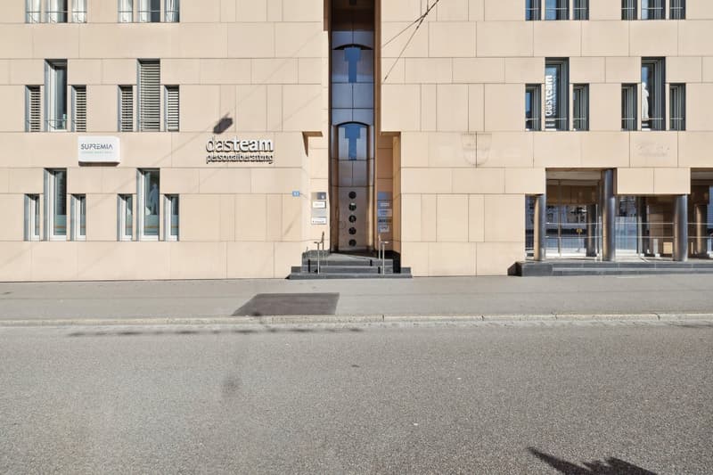 modern building with a glass entrance, white and blue colored signage, large windows