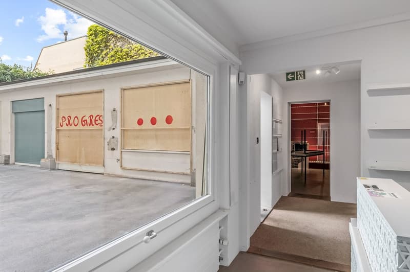 Garage with concrete floor, white walls, radiator, window, and door