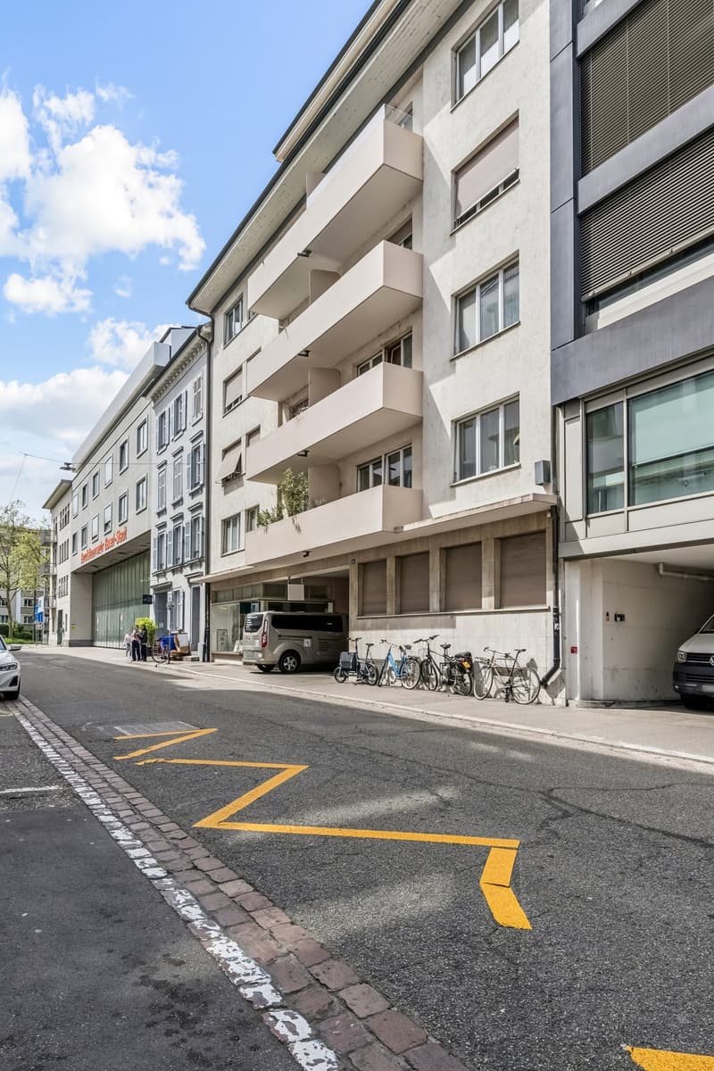 A multi-story building with balconies, a garage, and bicycles parked in front.
