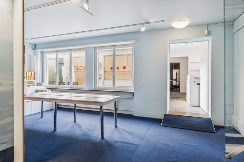 empty room, white walls, blue carpet, long table, windows, open door