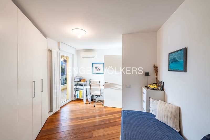 white walls, wooden floor, sliding glass door, single bed, shelves, picture frames, lamps, air conditioner, office chair, desk, cabinet, storage boxes