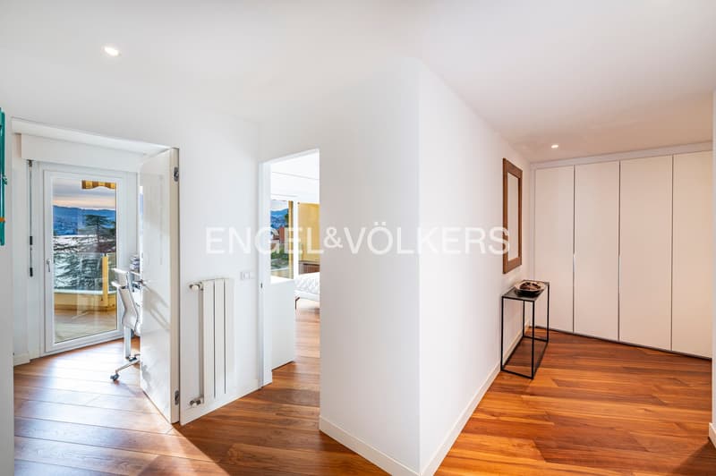 white walls, hardwood floors, open glass door to balcony, open hallway leading to other rooms