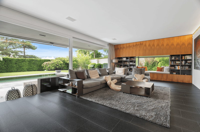 large floor-to-ceiling windows, sectional sofa, coffee table, rug, bookshelves, decorative items, lamp