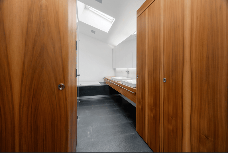 modern bathroom, glass walk-in shower, double vanity with 2 sinks, bathtub, skylight, wooden cabinetry, dark tiled floor