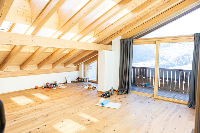 wooden floor, wooden ceiling beams, large glass windows, balcony with railings, outside view of mountains