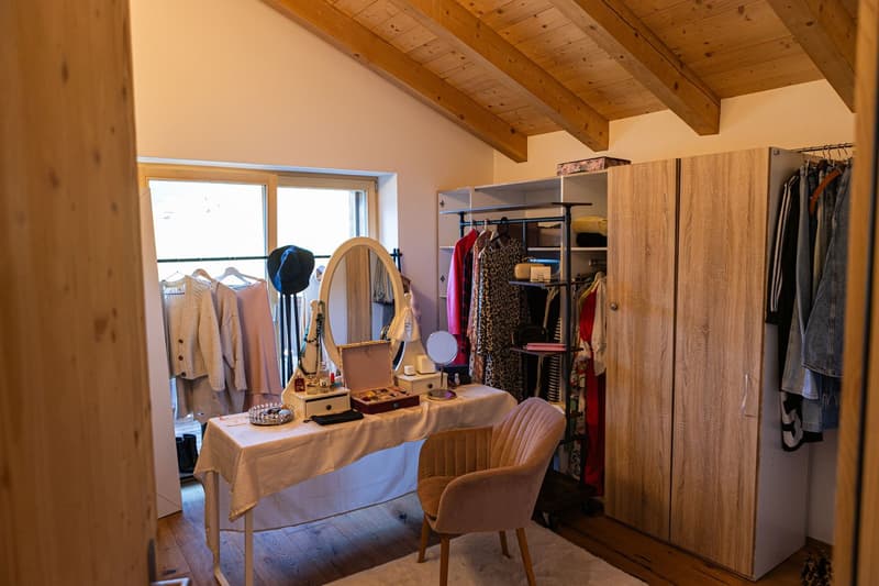 a room with a white desk, chair, a round mirror, and wardrobe