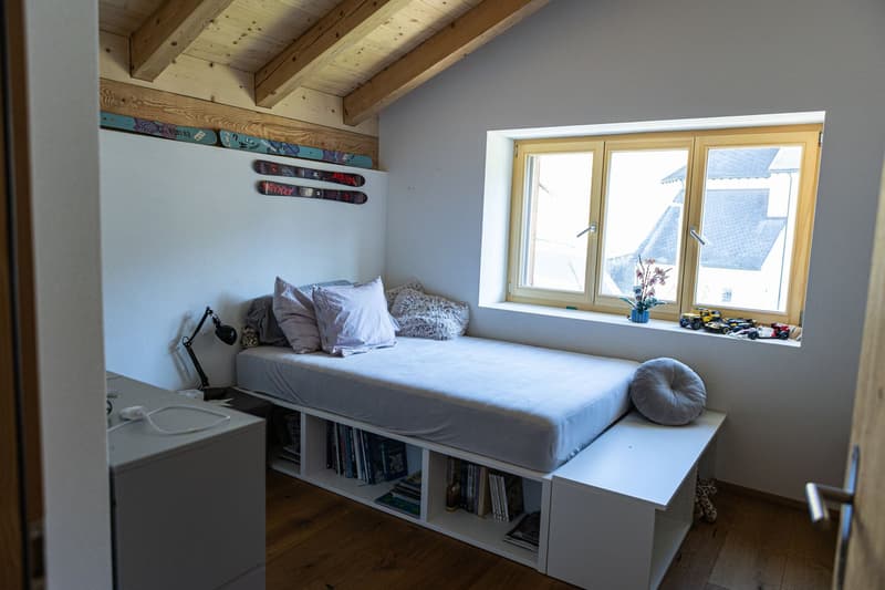 bedroom with a bed, cabinet, floor, window with toys and flowers