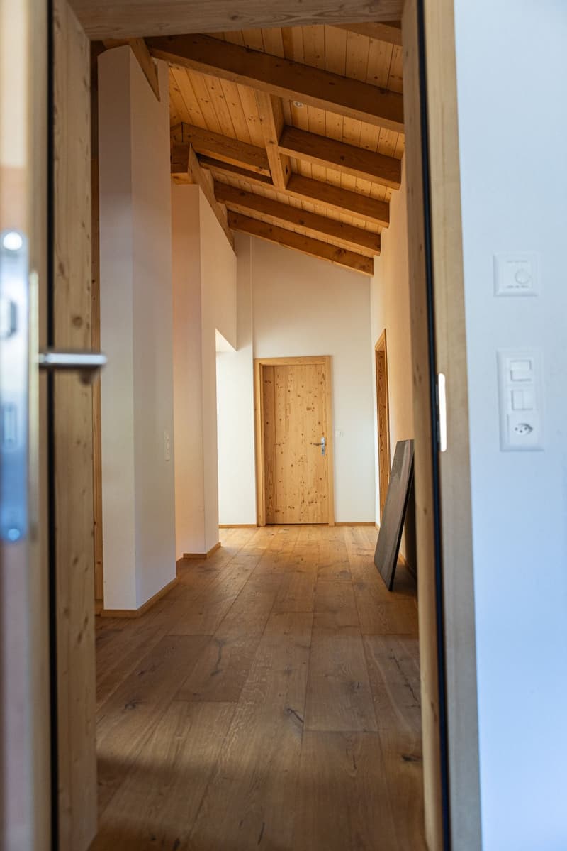 Wide hallway with wooden floor and exposed wooden beams ceiling