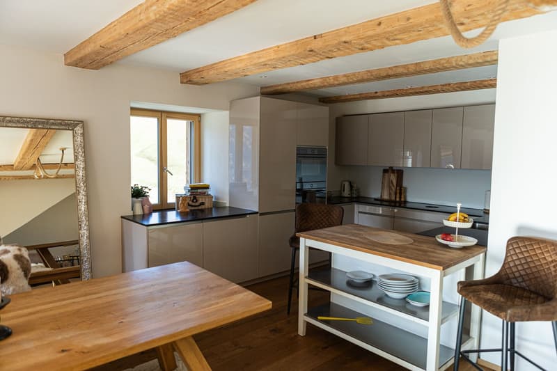 white cabinets, wooden table, island with shelves, open kitchen