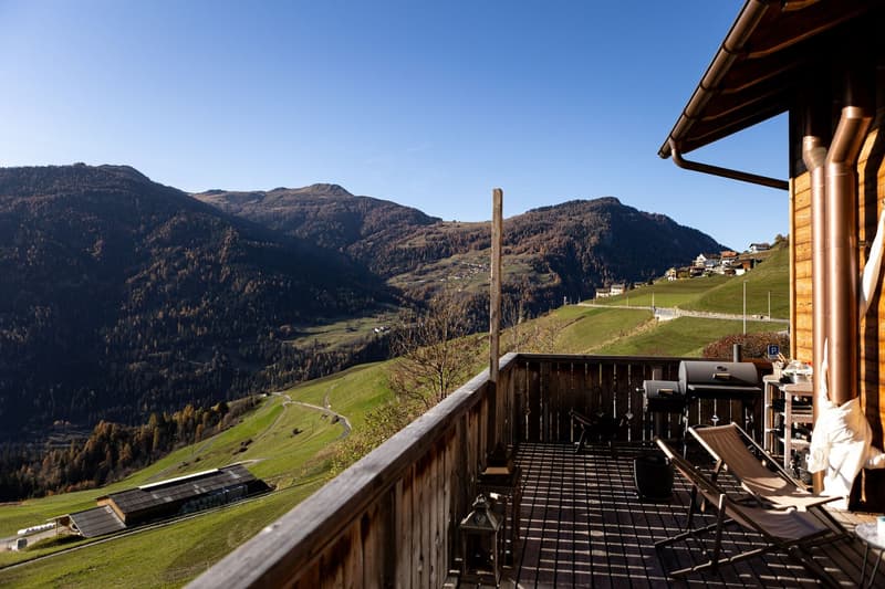Balcony with grill, chairs, lanterns, wooden floor, view of hills, mountains