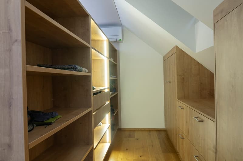 wooden closets, drawers, white walls, hardwood floors, lighted interior