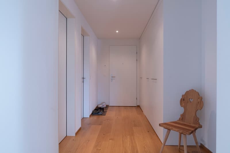 white walls, wooden floor, wooden chair, shoes on the floor
