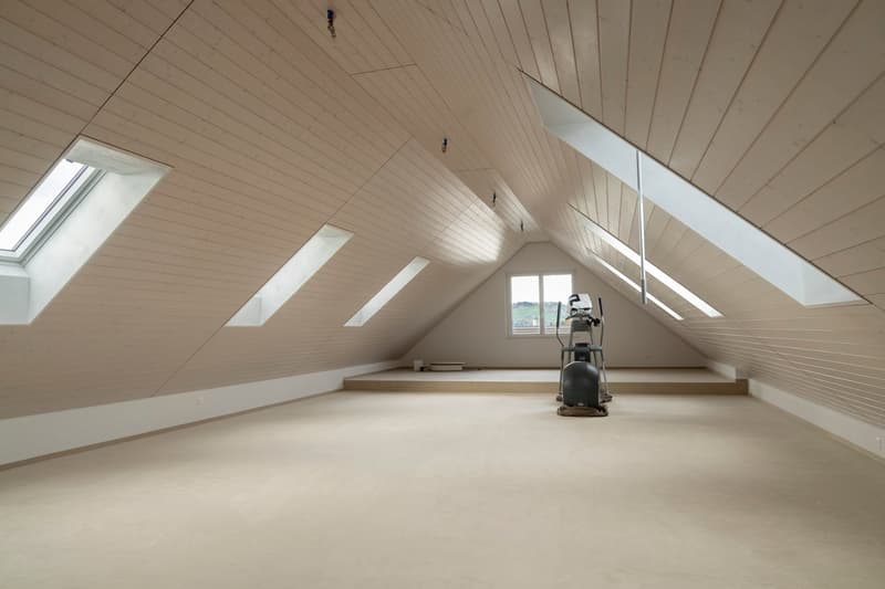 empty attic room with wooden panels on the ceiling and several windows