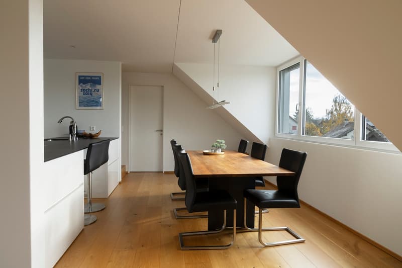 wooden dining table, black chairs, white kitchen counter, faucet, pendant lights, window