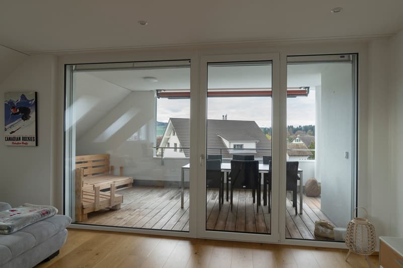 sliding glass doors, wooden flooring, wooden bed, balcony with table and chairs, cozy setting