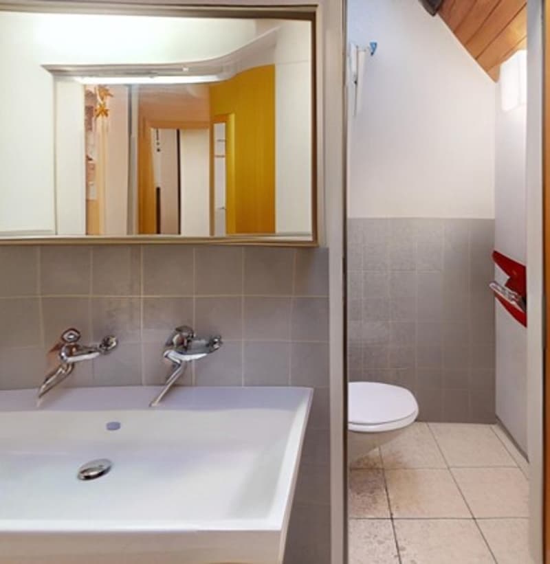 modern bathroom, white sink, mirror, toilet, tiled wall, silver faucets