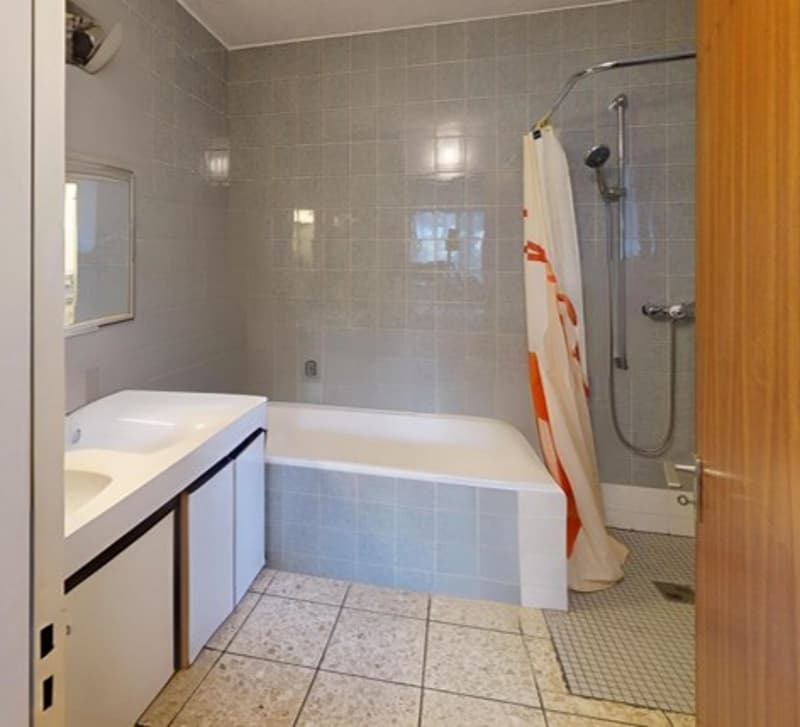 Bathtub with shower, sink, mirror, and tiled floor