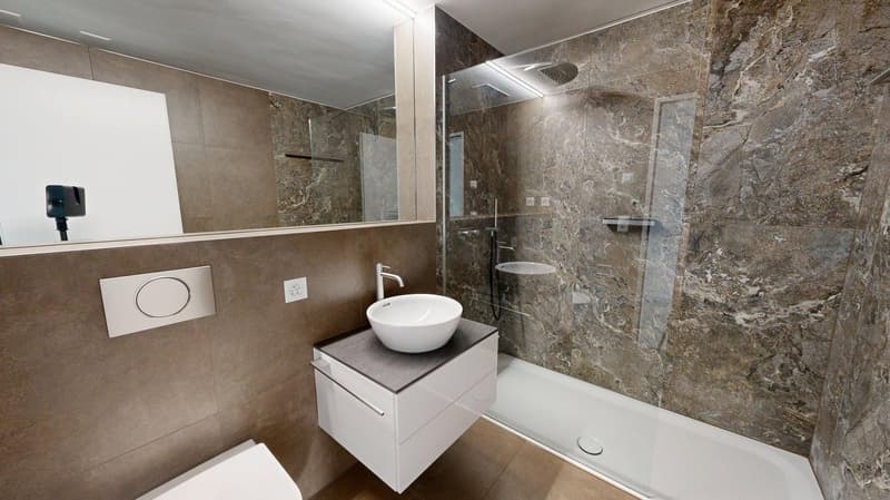 modern bathroom with marble tiles, white sink, glass shower enclosure, white toilet, mirror