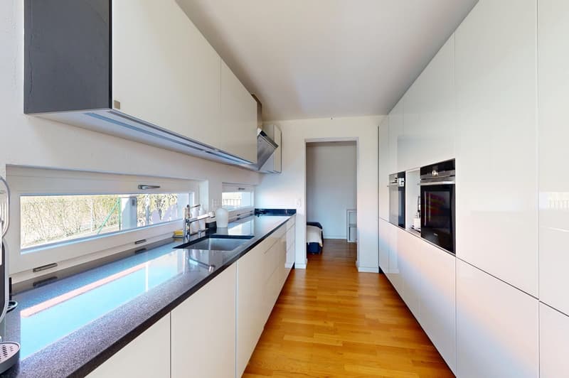 modern kitchen with white cabinets, black countertops, stainless steel appliances, wooden floor