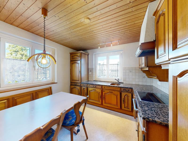 kitchen with wooden cabinets, dining table, pendant light, granite countertops, gas stove, sink, windows with curtains