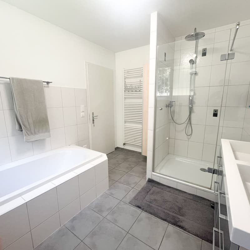 Tiled walls and floors, bathtub, glass shower enclosure, towel rack, toilet and sink