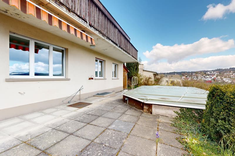 white house, balcony, covered terrace, covered pool, bushes, paved patio