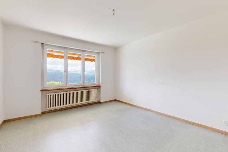 empty room, white walls, white floor, large window with view of mountains