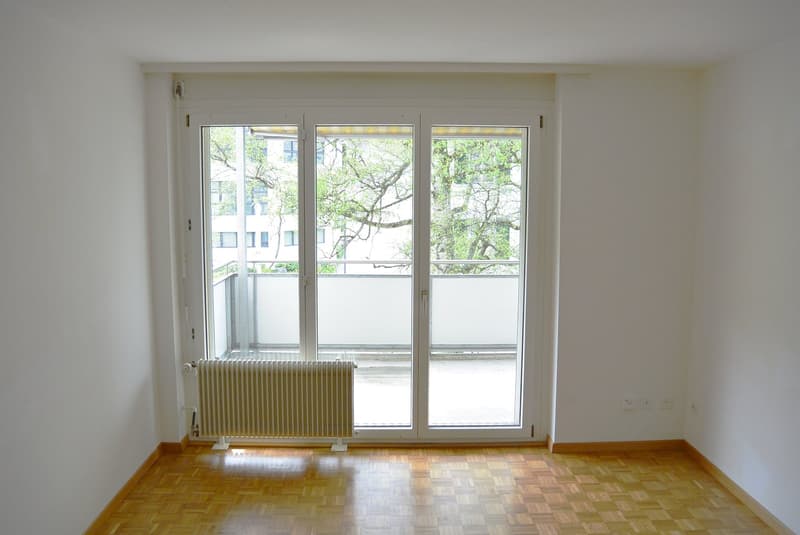 Sliding glass doors, balcony, wooden floor, white walls, radiator