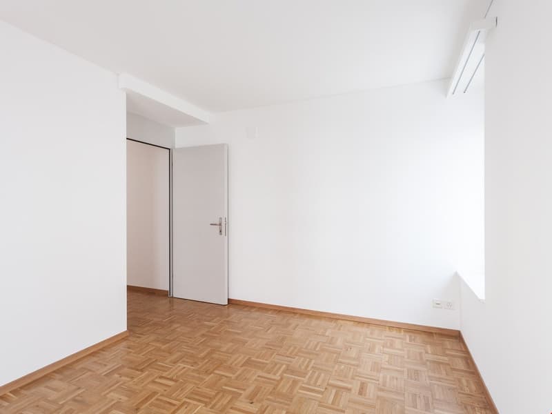empty room, white walls, wooden parquet floor, white door, power outlet