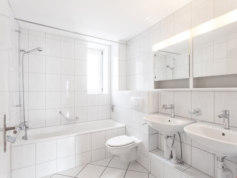 modern bathroom, white tiles, bathtub, two sinks, toilet, shower head, mirrors, faucets