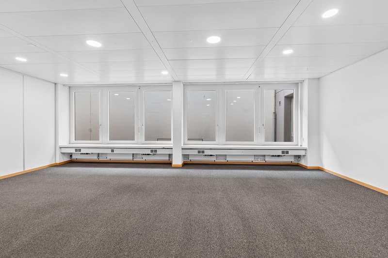 empty room, white walls, gray carpet, ceiling with recessed lighting, large windows with blinds