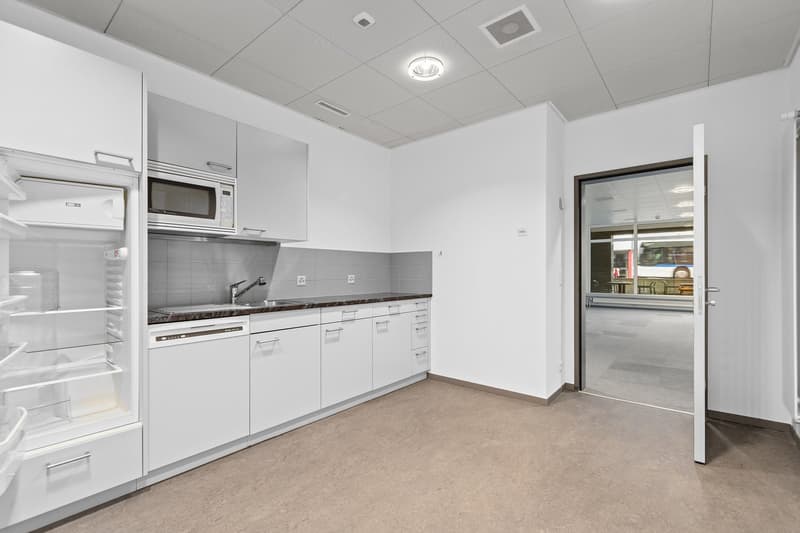 Modern kitchen with white cabinets, stainless steel appliances including a dishwasher, and granite countertops. The kitchen has a clean, minimalist design with ample storage space.