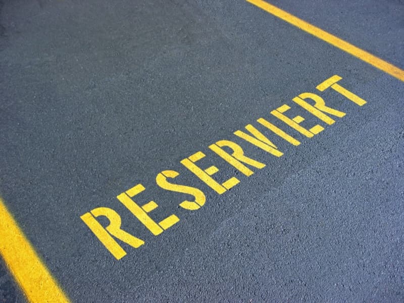 The image shows a parking lot surface with the word 'RESERVED' written in large yellow letters on the asphalt.