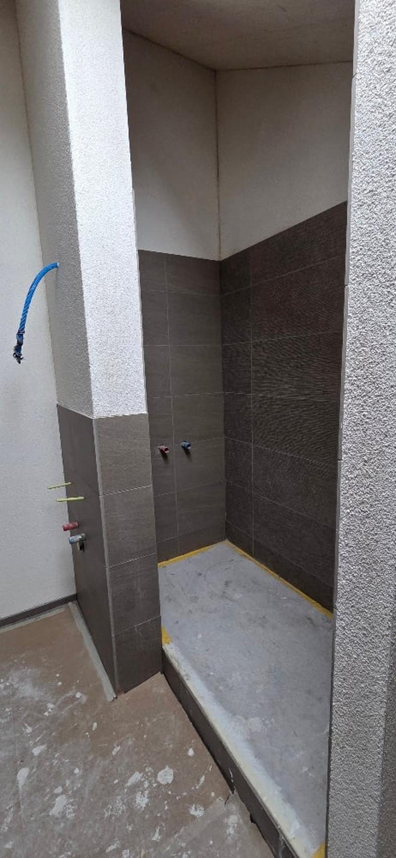unfinished shower area, tile walls, empty floor